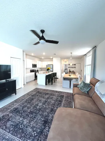 a living room with furniture kitchen view and a window