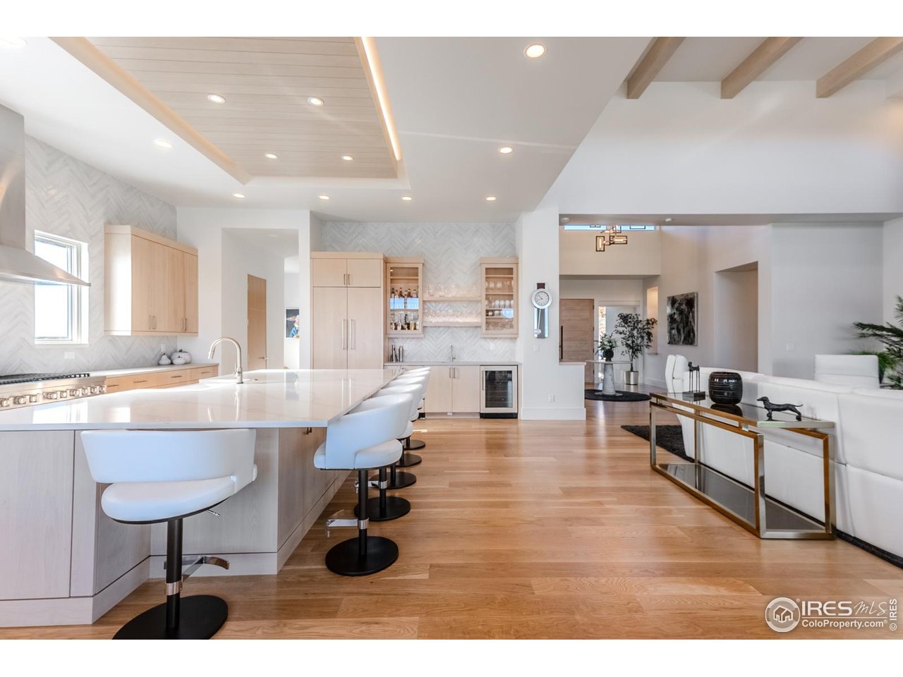 7572 Raphael Lane Littleton, CO 80125 - Photo 7 of 50 From the richness of the wide-plank oak floors to the commanding central island, and the wood-clad recessed ceiling washed in soft, integrated light above, the kitchen's architecture is orchestrated with intention, depth, and visual impact.