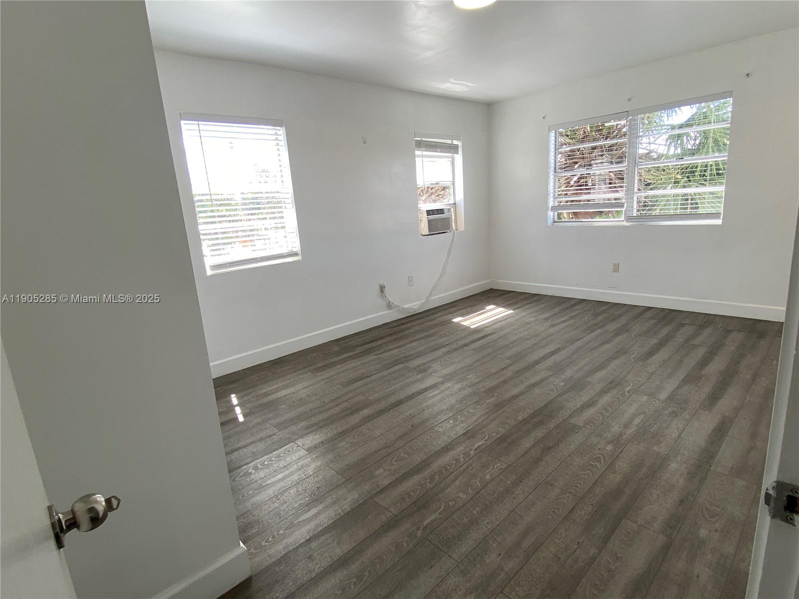 9025 Harding Avenue, Unit 1 Surfside, FL 33154 - Photo 12 of 25 a view of an empty room with wooden floor and a window