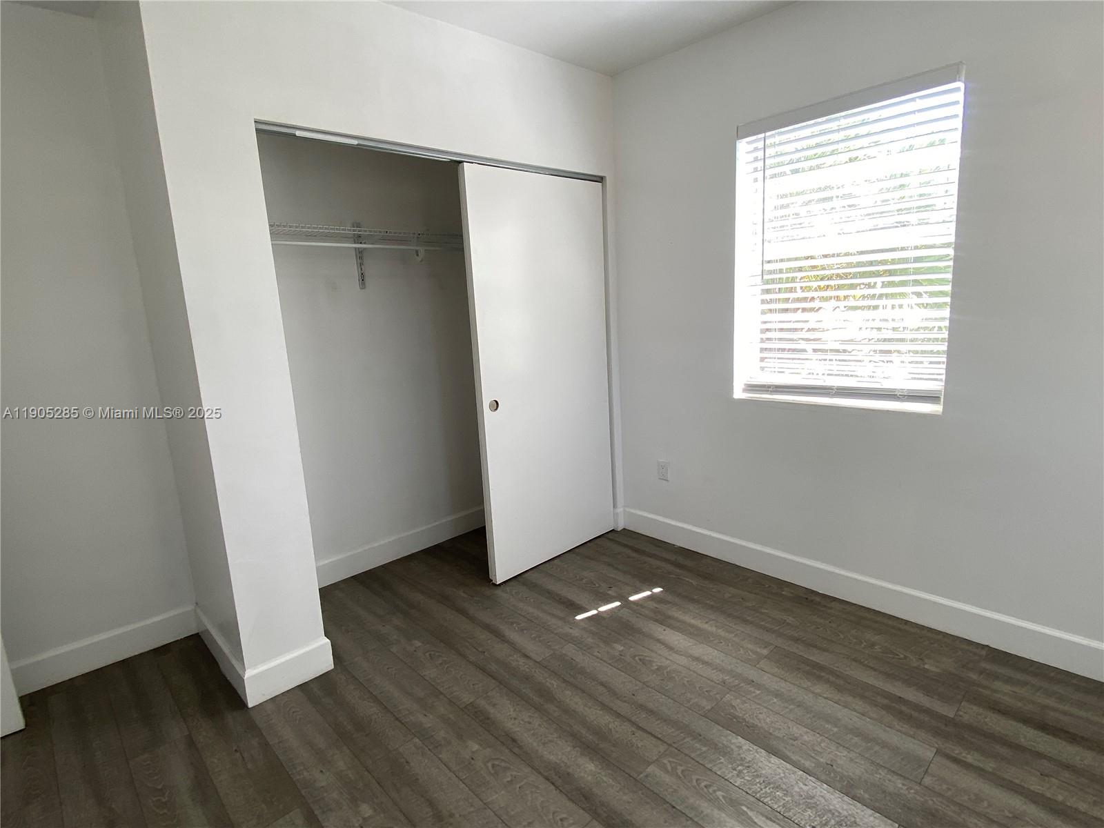 9025 Harding Avenue, Unit 1 Surfside, FL 33154 - Photo 13 of 25 an empty room with wooden floor and windows