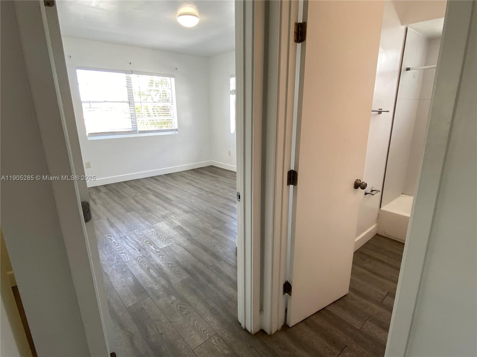 9025 Harding Avenue, Unit 1 Surfside, FL 33154 - Photo 16 of 25 an empty room with wooden floor and windows