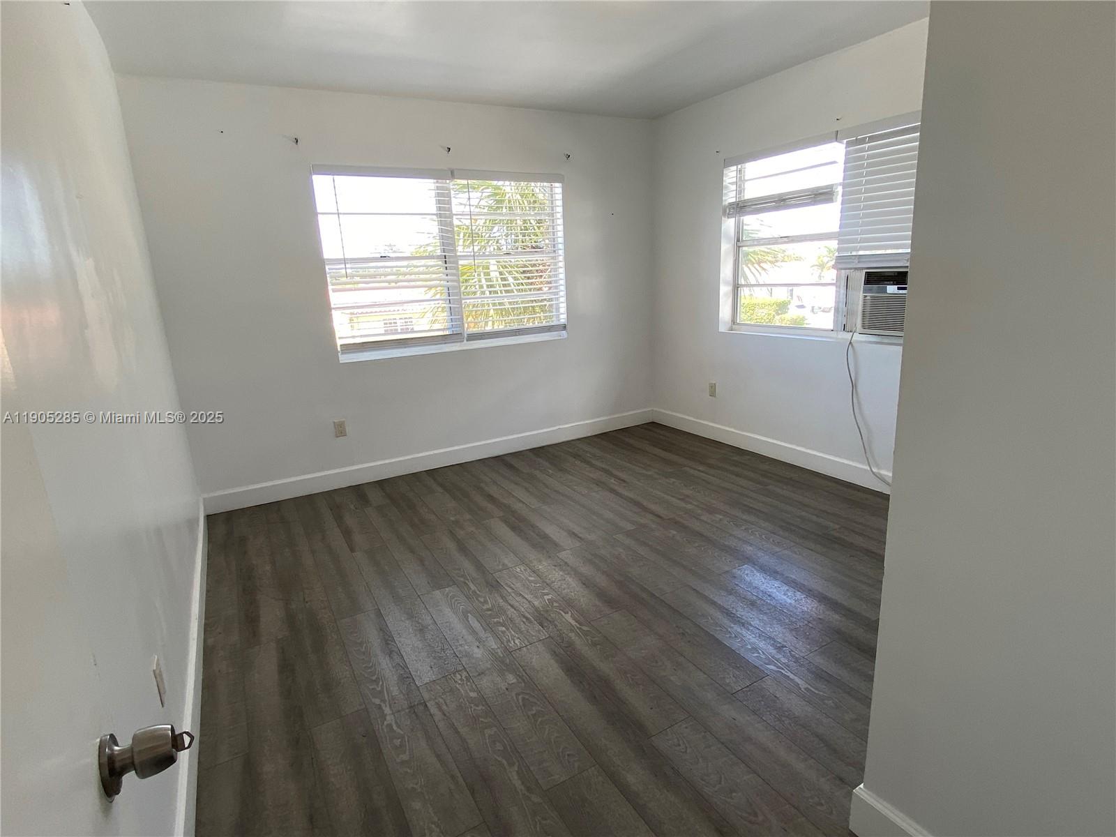 9025 Harding Avenue, Unit 1 Surfside, FL 33154 - Photo 17 of 25 an empty room with wooden floor and windows