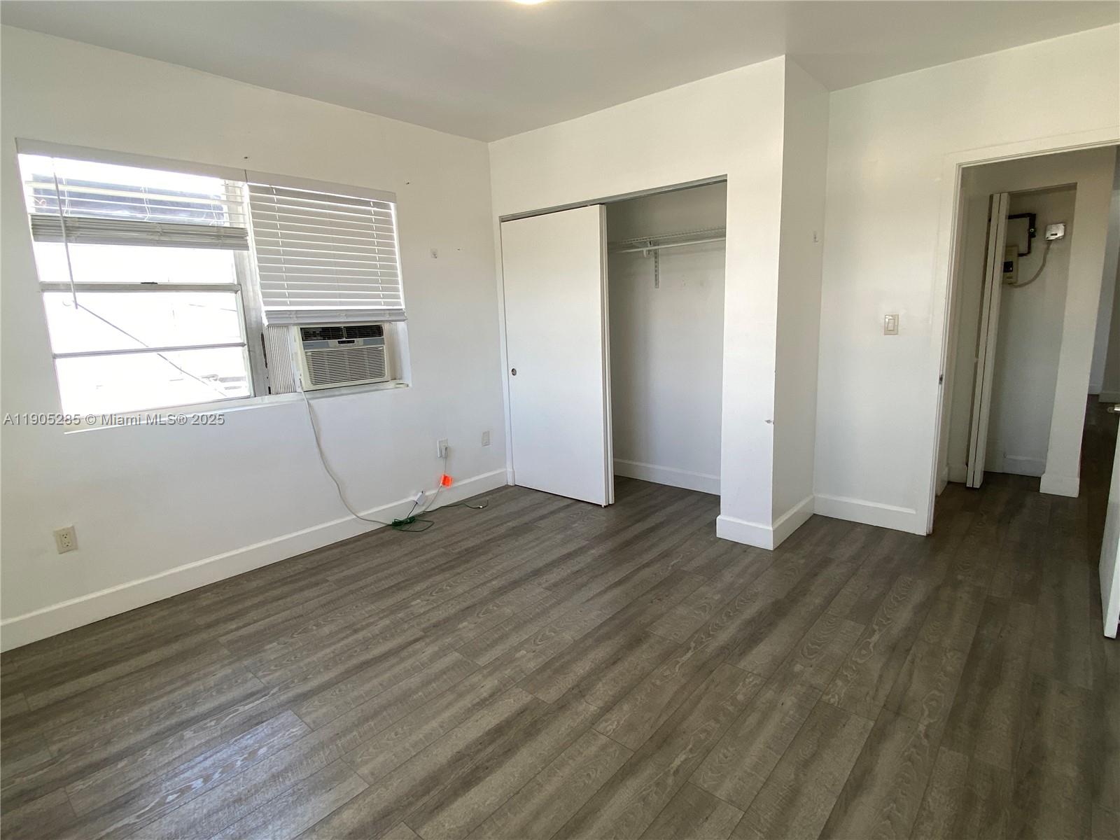 9025 Harding Avenue, Unit 1 Surfside, FL 33154 - Photo 18 of 25 an empty room with wooden floor and windows