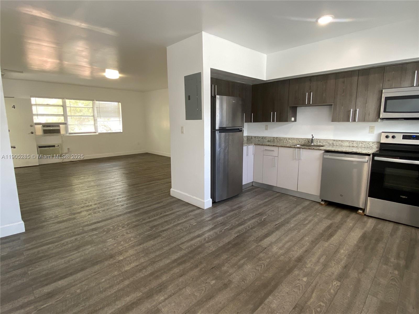 9025 Harding Avenue, Unit 1 Surfside, FL 33154 - Photo 8 of 25 a kitchen with stainless steel appliances granite countertop a refrigerator a sink dishwasher a stove with wooden floors and cabinets