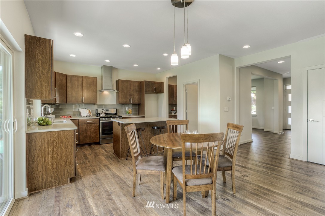 719 Southwest Langston Road Renton, WA 98057 - Photo 6 of 25 a kitchen with stainless steel appliances kitchen island granite countertop a table chairs and a refrigerator