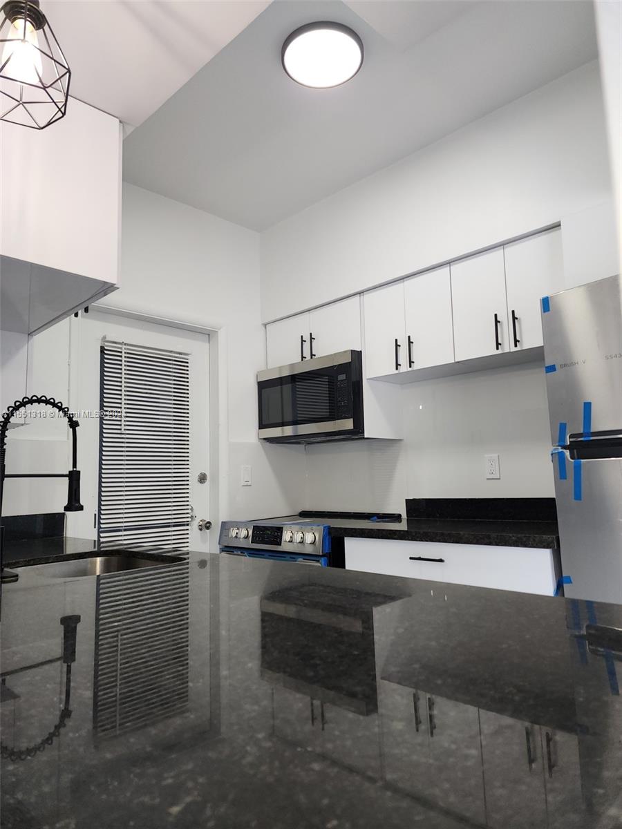 2101 Normandy Drive, Unit 204 Miami Beach, FL 33141 - Photo 14 of 30 a kitchen with stainless steel appliances granite countertop a stove a sink and a microwave