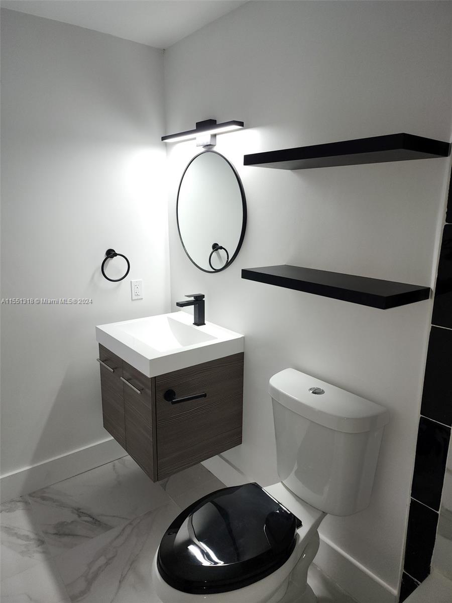 2101 Normandy Drive, Unit 204 Miami Beach, FL 33141 - Photo 22 of 30 a bathroom with a toilet sink vanity and mirror