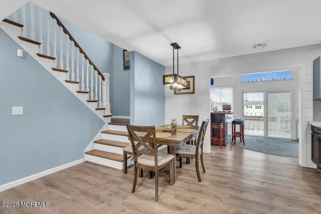 a kitchen with cabinets a sink dishwasher a stove and a dining table with wooden floor