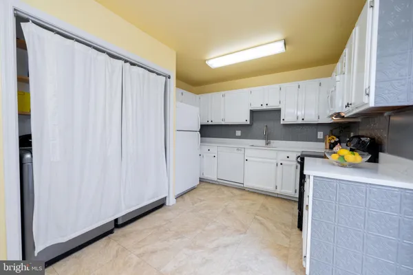 a kitchen with white cabinets and white appliances