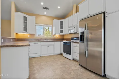 a kitchen with stainless steel appliances granite countertop a refrigerator sink and white cabinets