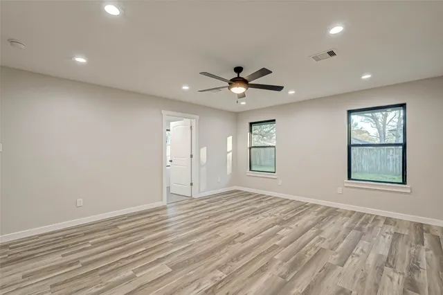 an empty room with windows and ceiling fan