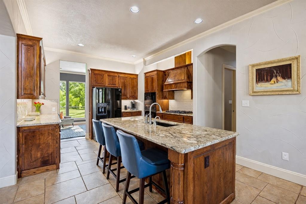 1520 Snider Court Lucas, TX 75002 - Photo 6 of 40 This well-appointed kitchen is open to the living room and has access to the formal dinging room (that is being used as a sitting room) offering a great entertaining flow. The kitchen features stunning solid wood cabinetry, a granite island with seating, and a gas range.