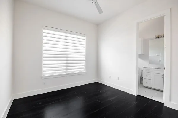 an empty room with wooden floor cabinet and windows