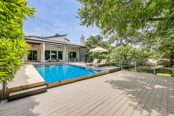 a view of swimming pool with lounge chair and dinning table under an umbrella