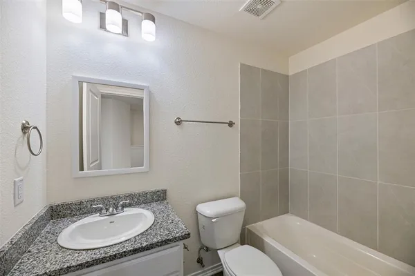 a bathroom with a granite countertop sink toilet a mirror and shower