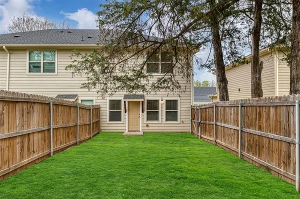 a view of a house with backyard and wooden fence