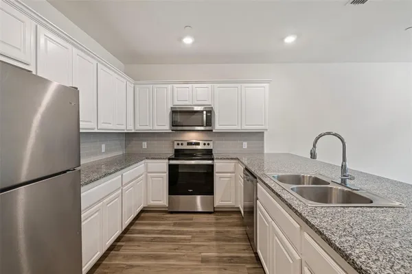 a kitchen with stainless steel appliances granite countertop a sink stove and refrigerator