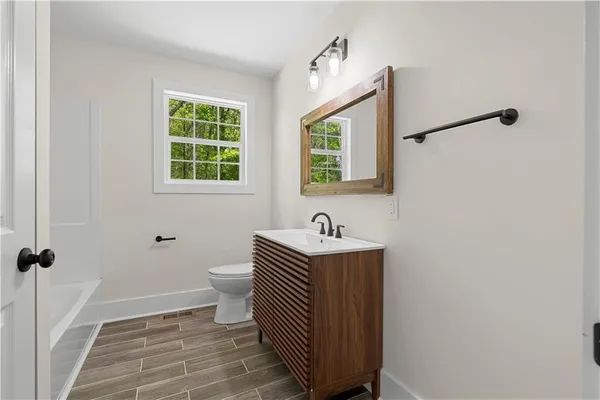 an empty room with wooden floor ceiling fan and windows