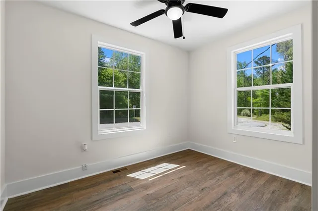 an empty room with windows and ceiling fan