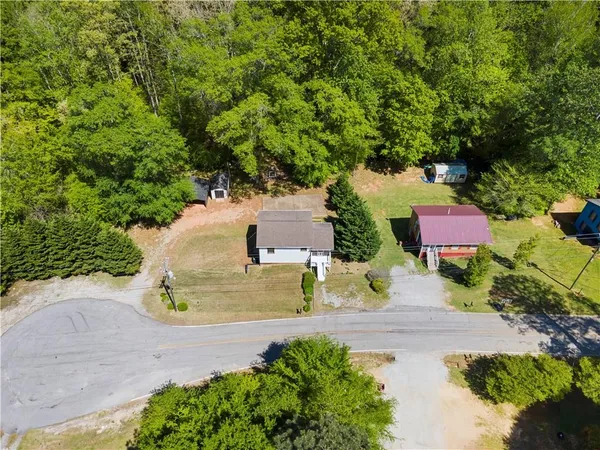 an aerial view of residential house with outdoor space and trees all around