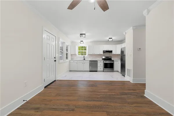 a view of empty room with wooden floor and fan
