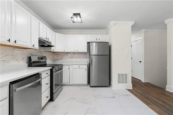 a kitchen with white cabinets stainless steel appliances and window