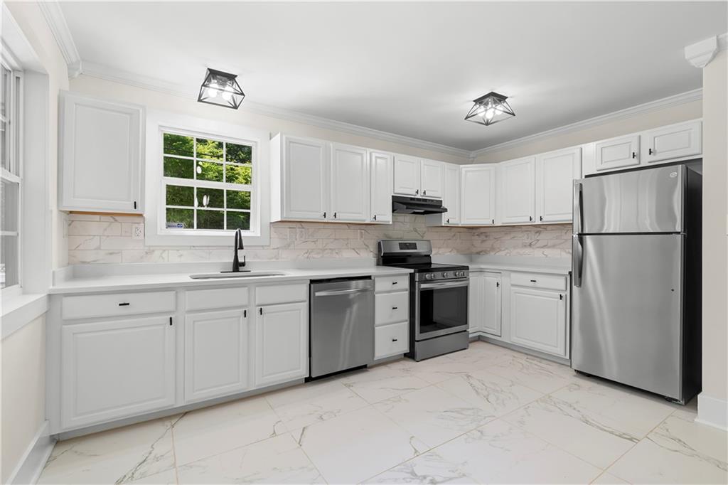 1271 Hayes Street Madison, GA 30650 - Photo 10 of 37 a kitchen with white cabinets stainless steel appliances and window