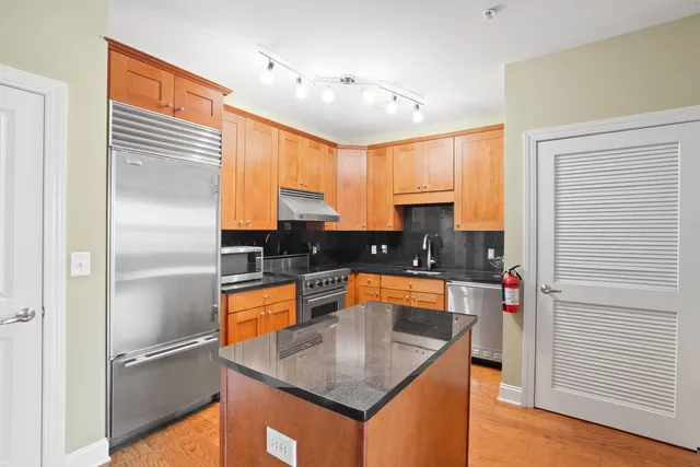 a kitchen with stainless steel appliances granite countertop a refrigerator a sink and a stove