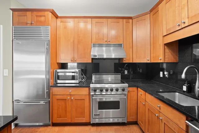 a kitchen with stainless steel appliances granite countertop a stove a sink and a microwave