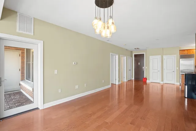 a view of an empty room with wooden floor and a chandelier
