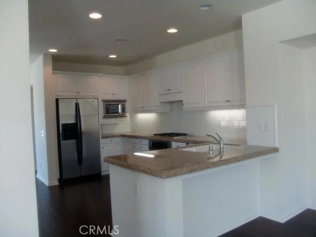 a kitchen with stainless steel appliances granite countertop a sink a stove and a refrigerator