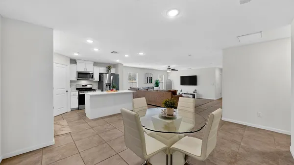 a kitchen with stainless steel appliances kitchen island granite countertop a refrigerator a stove a sink and white cabinets with wooden floor