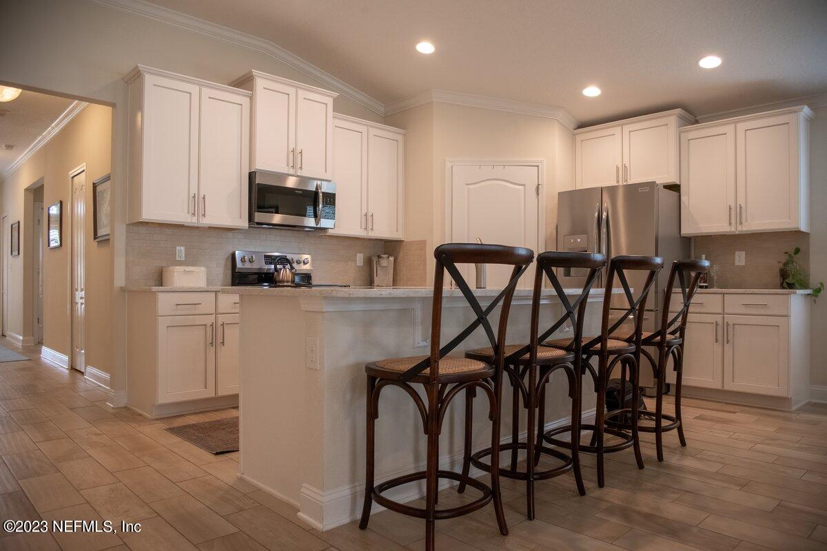 67 Salt Point St. Augustine, FL 32086 - Photo 11 of 39 a kitchen with stainless steel appliances a table chairs refrigerator and microwave
