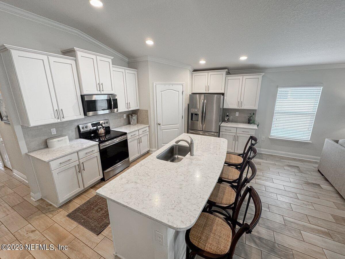67 Salt Point St. Augustine, FL 32086 - Photo 8 of 39 a kitchen with stainless steel appliances granite countertop a table chairs a refrigerator a stove a microwave and cabinets