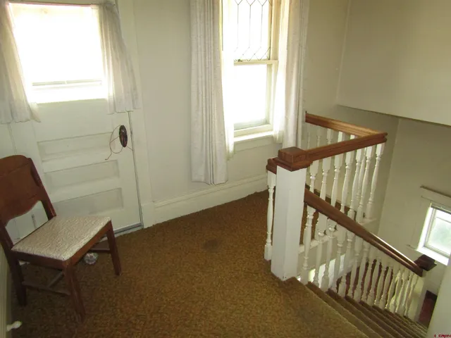 a view of an empty room with wooden floor and windows