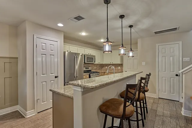 a kitchen with kitchen island granite countertop a sink stainless steel appliances and cabinets
