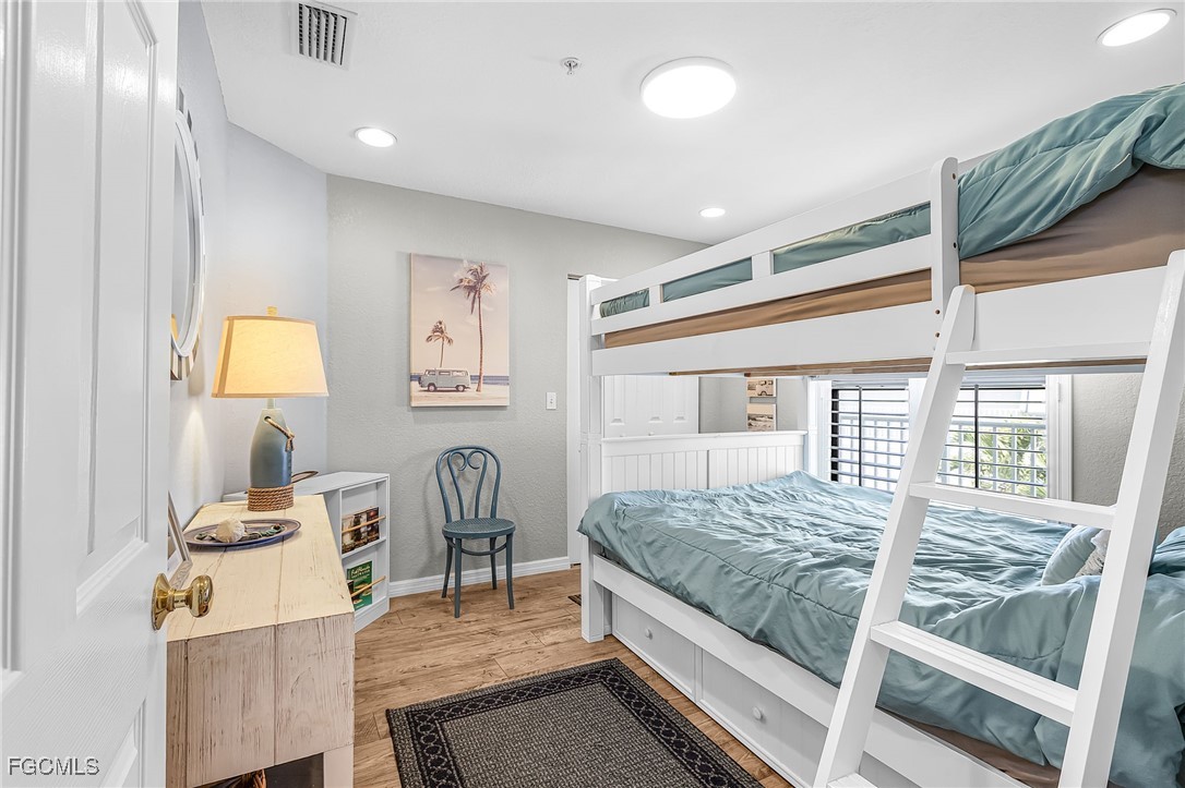 16641 Stringfellow Road, Unit 506 Bokeelia, FL 33922 - Photo 19 of 33 a bedroom with a bed and a table in it with wooden floor