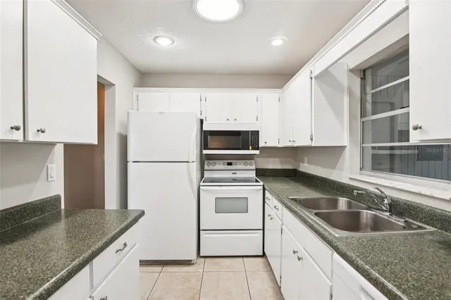a kitchen with granite countertop white cabinets and a sink