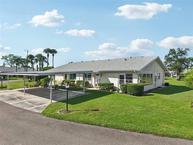 a view of a house with a yard and table and chairs under an umbrella