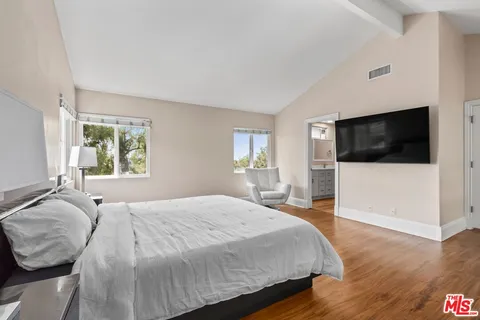 a spacious bedroom with a bed and a flat screen tv