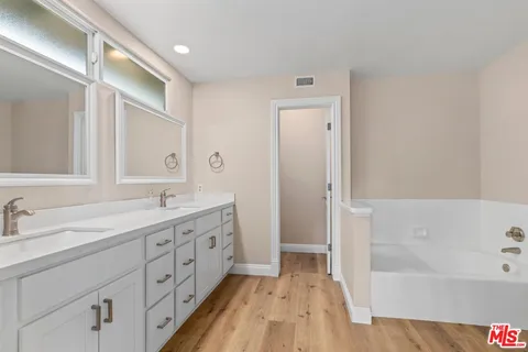 a bathroom with a double vanity sink a mirror and a bathtub