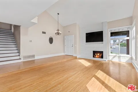a view of a livingroom with a fireplace a flat screen tv and staircase
