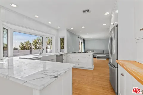 a large white kitchen with wooden floors and stainless steel appliances