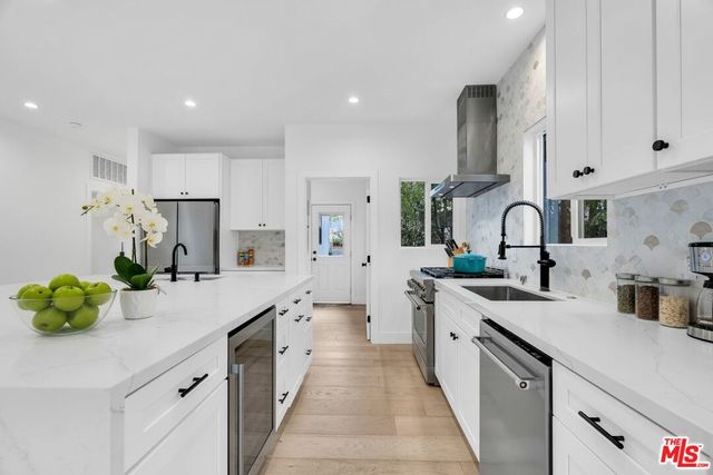 a large kitchen with stainless steel appliances a sink a counter top space and cabinets
