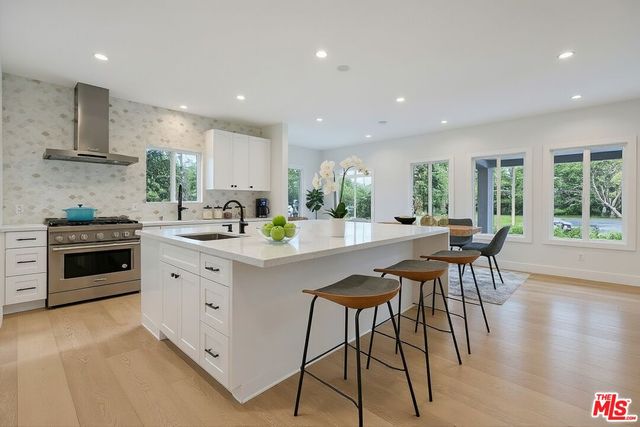 a kitchen with stainless steel appliances kitchen island granite countertop a stove a sink a dining table and chairs