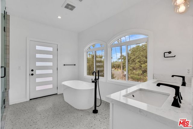 a spacious bathroom with a tub a sink and a large window