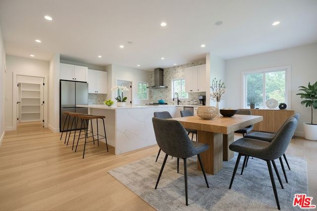 a dining area with stainless steel appliances kitchen island granite countertop a dining table chairs and window