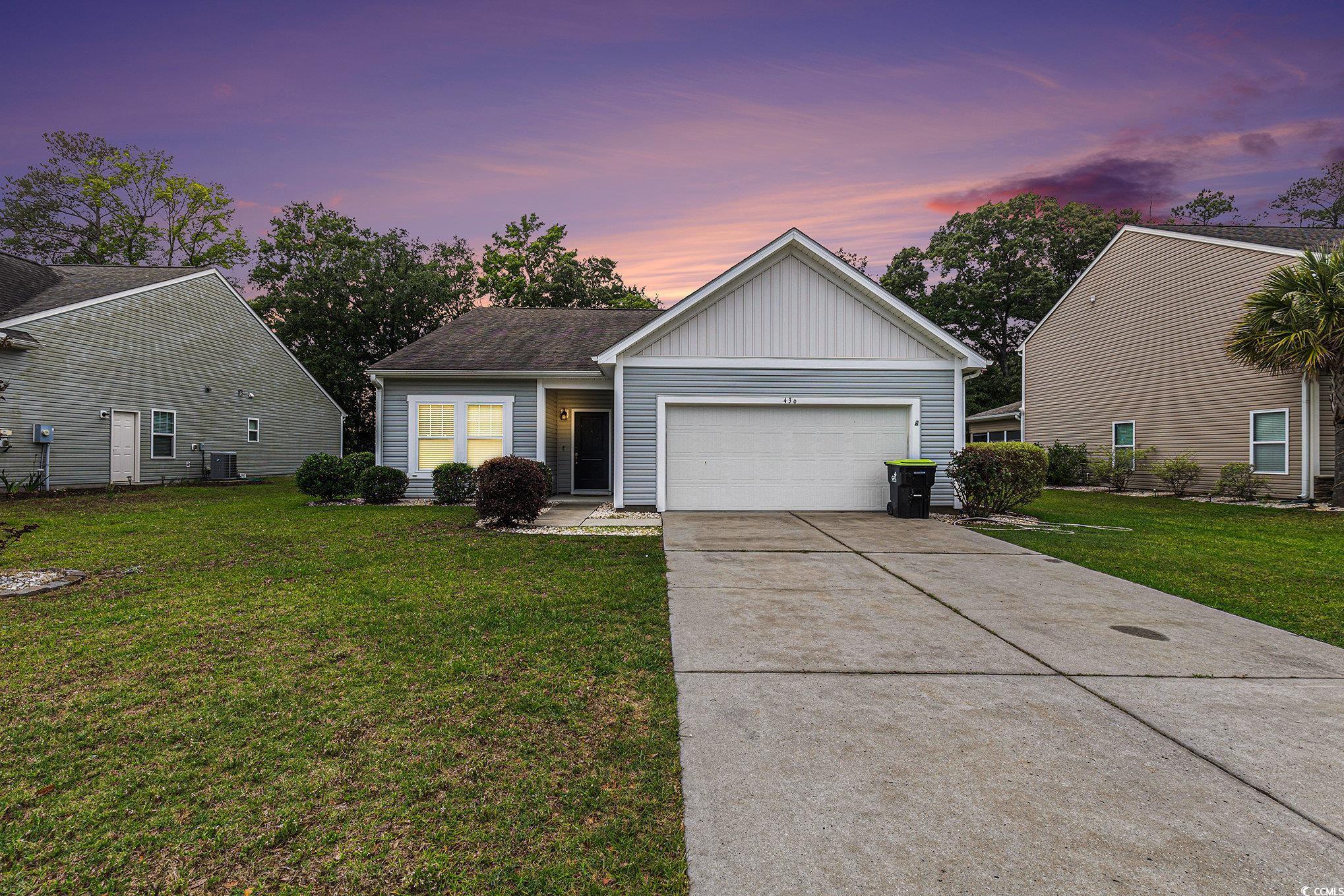 View of front of house featuring board and batten siding, driveway, a lawn, and a garage