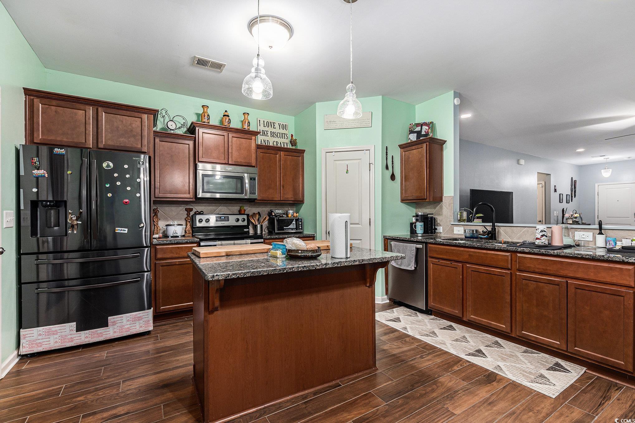 436 Cotton Grass Drive Loris, SC 29569 - Photo 8 of 33 Kitchen featuring appliances with stainless steel finishes, dark wood-style flooring, dark stone countertops, and tasteful backsplash