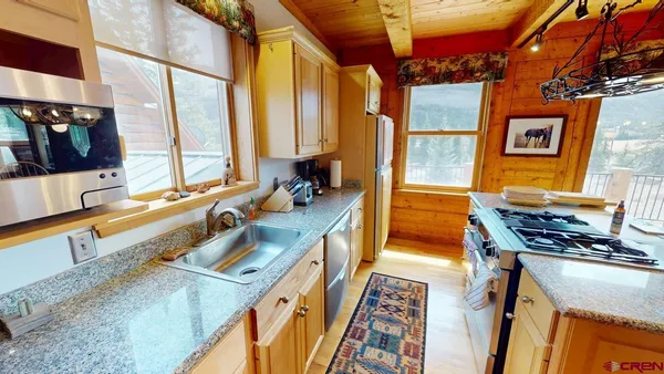 a living room with stainless steel appliances granite countertop furniture and a chandelier